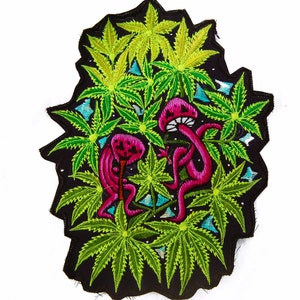 May include: Embroidered patch with a black backdrop, showcasing neon green cannabis leaves and two pink mushroom figures. The patch has a distinctive shape, with vibrant colours and detailed stitching.