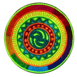 Pode incluir: Um patch redondo bordado com um design concêntrico vibrante. O patch apresenta um centro em espiral em tons de verde-azulado e verde, rodeado por anéis de laranja, vermelho e azul. A borda externa é verde escuro.