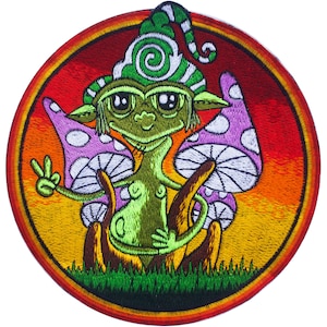 May include: A green fairy with a purple and white mushroom hat sits on two large mushrooms with purple caps and white stems. The fairy is holding up a peace sign with one hand and has a green, swirling hat. The background is a sunset with orange, yellow, and red colors.