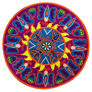 Pode incluir: Um patch redondo bordado com um design vibrante. O patch tem um fundo roxo com borboletas azuis e formas de folhas verdes. O centro tem um design azul e branco, com uma borda amarela em forma de sol e uma borda externa laranja.