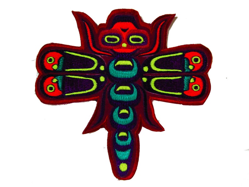 Op de afbeelding: Geborduurde patch met een gestileerd libellenontwerp. De patch heeft een rode rand, een donkerpaarse body en vleugels. De vleugels hebben groene en rode accenten en de body heeft turquoise en groene details. Op een witte achtergrond.