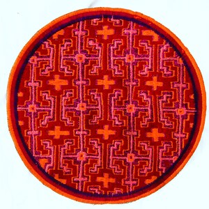 Pode incluir: Têxtil bordado redondo com um padrão geométrico repetitivo em tons de vermelho, laranja e rosa. O desenho é emoldurado por uma borda laranja, roxa e vermelha. Este têxtil feito à mão é adequado para decoração de casa, com cerca de 20 cm de diâmetro.