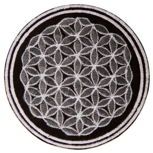 Puede incluir: Un parche circular con fondo negro y borde blanco y negro. El centro presenta un patrón bordado gris y blanco de la flor de la vida. El parche es probablemente para ropa o accesorios.
