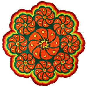 Puede incluir: Aplicación floral bordada de forma circular. Presenta colores naranja, verde y amarillo. El diseño muestra una flor central rodeada de ocho flores más pequeñas. Los bordes son festoneados y la costura es detallada.