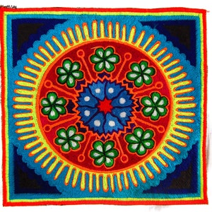 Pode incluir: Têxtil bordado quadrado com um design vibrante e simétrico. O motivo central é um padrão circular com um centro floral azul e branco, rodeado por flores verdes, detalhes laranja e uma borda amarela. A borda externa é azul e vermelha.
