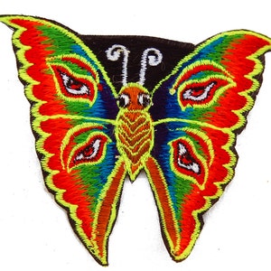May include: Embroidered butterfly patch with vibrant colors. The wings feature red, orange, blue, and green hues, outlined in yellow. The butterfly's body is brown and yellow, with black antennae. This decorative patch is ideal for adding flair to clothing or accessories.