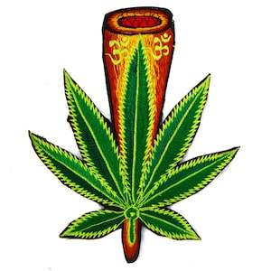 May include: Embroidered patch depicting a green cannabis leaf with yellow and black detailing. A cylindrical design in red, orange, and yellow is at the top, with the Om symbol. The patch is on a white background.