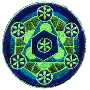 Pode incluir: Um remendo redondo bordado com um design geométrico verde, azul e roxo. O centro do remendo apresenta uma estrela de seis pontas com um design floral em seu interior. A estrela é cercada por cinco flores menores.