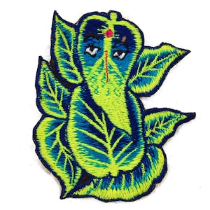 Pode incluir: Patch bordado com a representação de Ganesha, uma divindade hindu. O patch apresenta um design detalhado em tons de azul, verde e amarelo. Inclui um ponto vermelho na testa e um nariz em forma de tromba. Ideal para roupas ou acessórios.