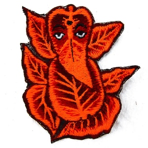 May include: Embroidered patch featuring a stylized orange depiction of the Hindu deity Ganesha. The patch showcases intricate stitching, with a detailed face, large ears, and a trunk. The design is set against a white background.