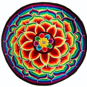 Puede incluir: Un parche bordado circular con un diseño floral vibrante y multicolor. El parche presenta una flor central con pétalos rojos, rodeada de capas de pétalos de colores del arcoíris. Un borde negro enmarca el diseño.