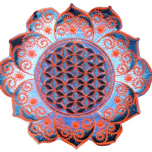 May include: Embroidered patch featuring a lotus flower design with a central Seed of Life pattern. The patch has a blue and orange color scheme, with intricate details in the petals and center. The patch is circular and has a detailed, textured appearance.