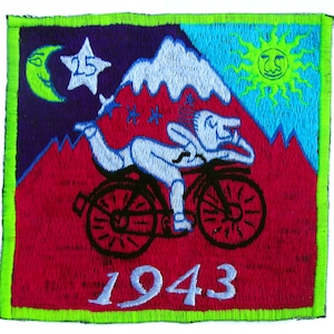 May include: Embroidered patch with a cartoon cyclist riding a bicycle, set against a mountain range. The patch features a smiling sun, a crescent moon, and the number 25 in a star. The year 1943 is displayed at the bottom. The patch has a green border.