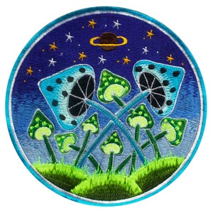 May include: Embroidered patch featuring a whimsical design of stylized mushrooms in shades of blue and green, set against a starry night sky with a planet. The patch has a circular shape with a blue border and green grass at the bottom.