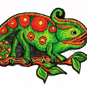 Peut inclure: Patch brodé vert et rouge d'un caméléon avec une longue langue, assis sur une branche avec des feuilles vertes.