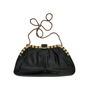 May include: A black snakeskin clutch bag with a gold chain strap and a gold clasp.