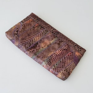 May include: A purple and brown snakeskin clutch purse with a patchwork design.