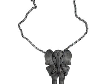 May include: A silver-toned elephant pendant necklace. The elephant pendant is detailed with large ears, a trunk, and legs. The necklace chain is a linked design. The jewelry is displayed against a white background.