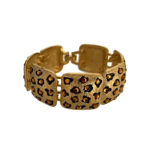 May include: Gold tone bracelet with a leopard print design. The bracelet is made of metal and has a chain link closure.