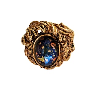 May include: A gold ring with an oval-shaped blue opal stone set in a detailed, ornate design.