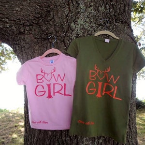 May include: Two pink and green t-shirts with the text "BOW GIRL" and a heart with antlers above the word "BOW". The text is in red and the shirts have the words "Love with Love" printed on the bottom.