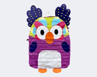 May include: A colorful owl-shaped piñata with a purple body, white belly, and orange feet. The owl's face features large white eyes, an orange beak, and a multi-colored head with blue wings dotted with yellow circles. A fun party decoration.