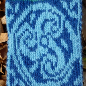 May include: Blue knitted fabric with a white and blue patterned design. The fabric has a textured surface and a white, red, and yellow border.