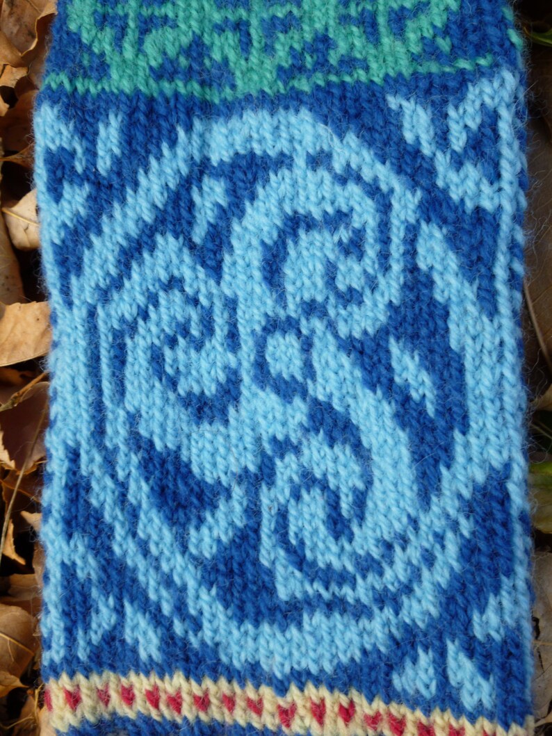 May include: Blue knitted fabric with a white and blue patterned design. The fabric has a textured surface and a white, red, and yellow border.