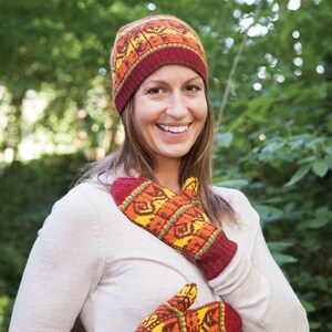 Könnte beinhalten: Eine Frau trägt eine rote, orange und gelbe Strickmütze und passende Fäustlinge. Mütze und Fäustlinge haben ein geometrisches Muster.