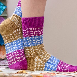 May include: A pair of colourful knitted socks with a geometric pattern in shades of brown, blue, white and pink.