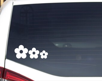 May include: A white car with a rear window sticker of four white stylized flowers.