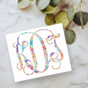 May include: A white square card featuring a large, decorative monogram letter O in the center. The letter is filled with a vibrant, multi-colored abstract pattern consisting of shades of orange, blue, pink, yellow, and turquoise in a swirling design.