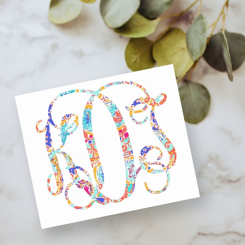 May include: A white square card featuring a large, decorative monogram letter O in the center. The letter is filled with a vibrant, multi-colored abstract pattern consisting of shades of orange, blue, pink, yellow, and turquoise in a swirling design.