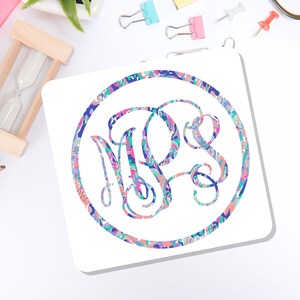 May include: A square white coaster featuring a circular border and a central monogram with the letters MPS. The design is filled with a vibrant, multi-colored abstract pattern in shades of pink, blue, purple, and teal, creating a marbled effect.