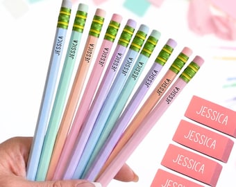 May include: A set of pastel-colored pencils and rectangular erasers, each personalized with the name JESSICA printed in black or white. The pencils feature green metal ferrules and pink erasers, arranged in a fan shape alongside stacked erasers.