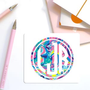 May include: A square white sticker featuring a circular design with a vibrant, multi-colored abstract pattern in shades of pink, blue, yellow, and teal. The center displays the white monogram letters CJB in a bold, block-style serif font.