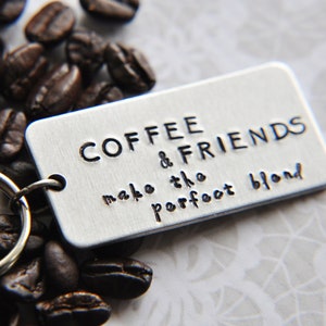 May include: Silver keychain with a coffee bean design and the text "Coffee & Friends make the perfect blend".