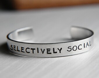Könnte beinhalten: Ein silbernes Armband mit der Gravur "Selectively Social".