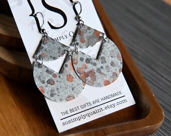Könnte beinhalten: Ein Paar grau-rot gesprenkelte Ohrringe mit geometrischem Design. Die Ohrringe werden auf einer weißen Karte mit dem Text "Simply Quaint" und der Etsy-Shop-URL präsentiert. Die Ohrringe befinden sich auf einem Holztablett.