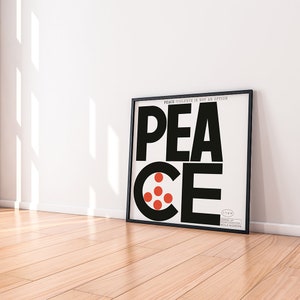 Puede incluir: Una impresi&oacute;n enmarcada en blanco y negro con la palabra "PEACE" en letras negras en negrita. La "E" se reemplaza por un c&iacute;rculo rojo con cuatro c&iacute;rculos rojos m&aacute;s peque&ntilde;os dentro. El texto "PEACE/VIOLENCE IS NOT AN OPTION" est&aacute; impreso en letras blancas peque&ntilde;as en la parte superior de la impresi&oacute;n.