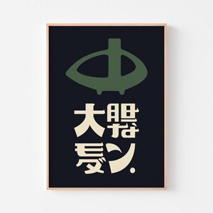 May include: A framed art print featuring a dark green abstract shape above Japanese characters in cream against a black background. The artwork has a minimalist design with a wooden frame.
