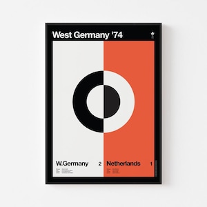 May include: Framed poster with a black border. The design is split vertically, with a white and black section on the left and an orange section on the right. The text "West Germany '74" is at the top, and "W. Germany 2 Netherlands 1" at the bottom.