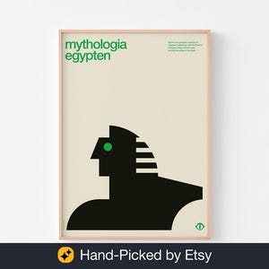 May include: A framed art print with a minimalist design. The print features the words "mythologia egypten" in green. The artwork depicts a black silhouette of a sphinx with a green eye against a cream background. The frame is a light wood colour.