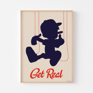 May include: A framed art print featuring a navy blue silhouette of a puppet-like figure with red strings. The figure is wearing a cap and sneakers. The words "Get Real" are written in red script at the bottom of the print.