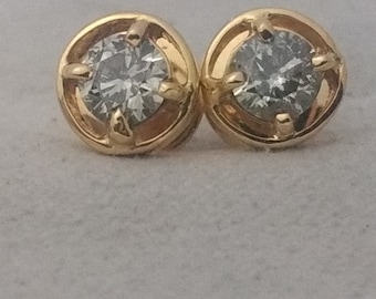 May include: A pair of gold stud earrings with a clear round gemstone in the center of each.