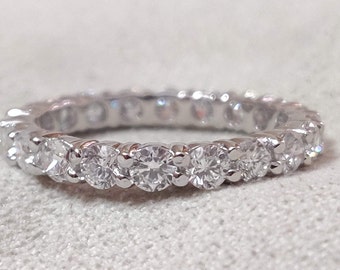 May include: A silver band ring with a row of round, clear diamonds set in a pave setting.