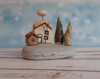 Small sculpture art of a ceramic houses and trees on a flat gray beach stone, a one of a kind home decor