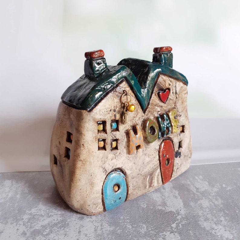 Ceramic house sculpture with the word HOME and a tiny metal Etsy