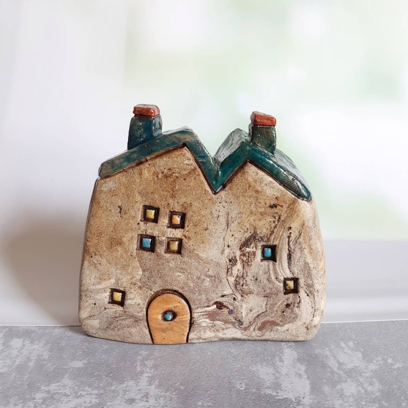Ceramic house sculpture with the word HOME and a tiny metal Etsy