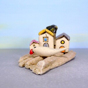 Whimsical white miniature ceramic houses with anOlive tree on a unique beach stone image 3